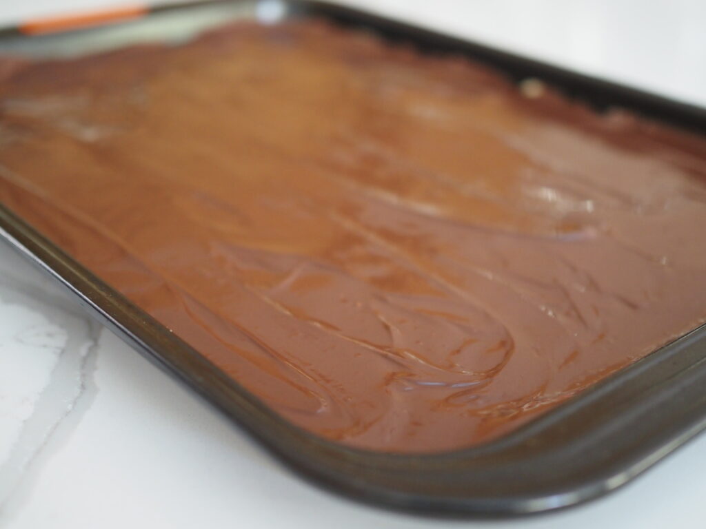 Chocolate smoothed over caramel and cookie base