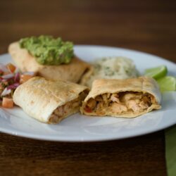 Plated chimichangas with guacamole, rice and pico do gallo